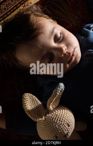 Bébé garçon dormant avec sa poupée de lapin. Banque D'Images