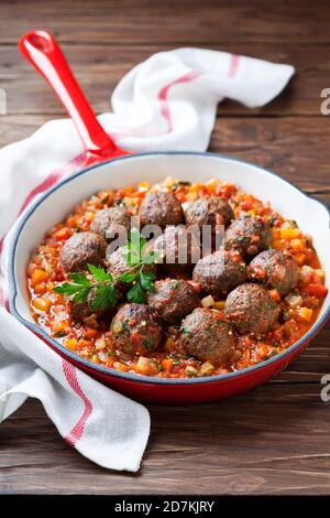 Boulettes de viande avec sauce végétale dans une poêle en fonte sur fond de bois, foyer sélectif Banque D'Images