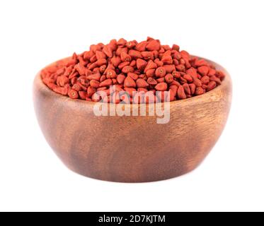 Graines d'annatto dans un bol en bois, isolées sur fond blanc. Graines d'achiote, bixa orellana. Colorant naturel pour la cuisine et la nourriture. Banque D'Images