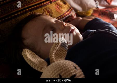 Bébé garçon dormant avec sa poupée de lapin. Banque D'Images