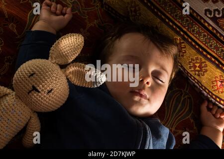 Bébé garçon dormant avec sa poupée de lapin. Banque D'Images