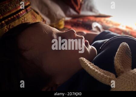 Bébé garçon dormant avec sa poupée de lapin. Banque D'Images