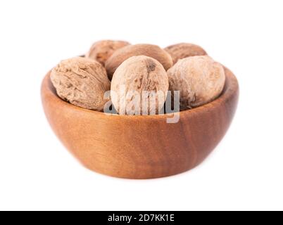 Muscade isolée sur fond blanc. Sécher la muscade entière dans un bol en bois. Gros plan. Banque D'Images