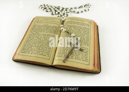 Ouvert le vieux livre de prière catholique Saint brun Trésor de la Coeur sacré et perles blanches crucifix avec sainte croix isolée sur fond blanc Banque D'Images