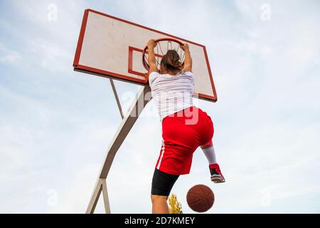 Femmes jouant au basket-ball sur le terrain de rue. Une femme jouant au streetball fait du slam punk dans un match de basket-ball. Banque D'Images