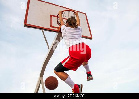 Femmes jouant au basket-ball sur le terrain de rue. Une femme jouant au streetball fait du slam punk dans un match de basket-ball. Banque D'Images