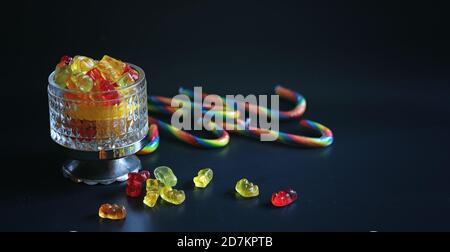 Marmelade dans un vase sur la table. Bonbons dans un bol sur un fond noir. Jelly multicolore des bonbons pour les enfants. Banque D'Images