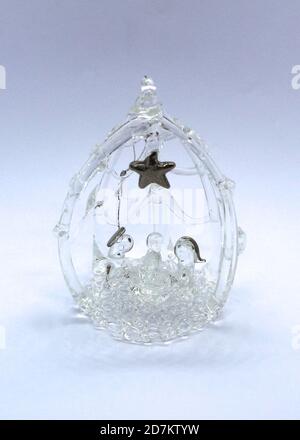 Photo d'un petit verre suspendu nativité décoration d'arbre de Noël avec une étoile argente fortement éclairée gros plan sur un fond blanc Banque D'Images