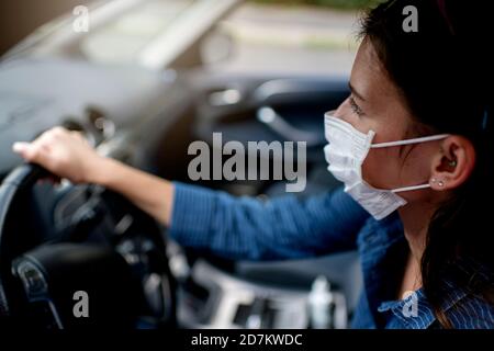 Femme dans un masque de protection conduisant une voiture Banque D'Images