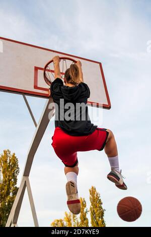 Femmes jouant au basket-ball sur le terrain de rue. Une femme jouant au streetball fait du slam punk dans un match de basket-ball. Banque D'Images