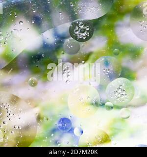 Texture de l'huile et de l'eau se mélangeant sur un fond flou pour former des cercles et des bulles Banque D'Images