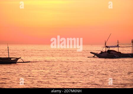 Boracay, Philippines - 27 janvier 2020 : coucher de soleil sur l'île de Boracay. Voile et autres bateaux traditionnels avec des touristes sur la mer sur le fond de Banque D'Images