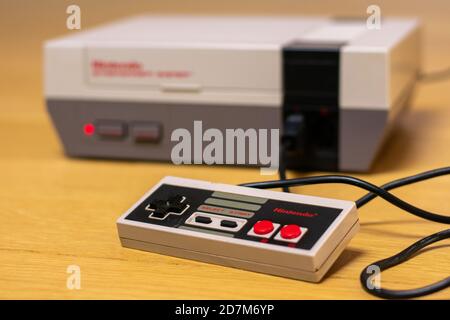 Le contrôleur d'un système de divertissement Nintendo sur un plancher en bois branché à la console. Banque D'Images