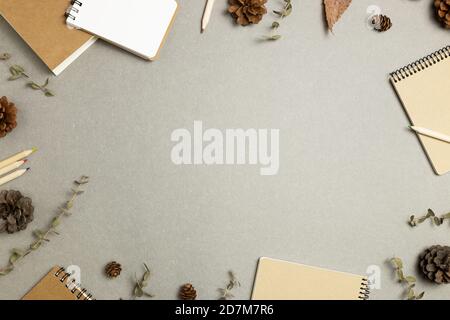 Carnets avec feuilles sèches, cônes en pin sur fond gris. pose à plat, vue de dessus, espace de copie. Lieu de travail et d'étude. Concept automne et hiver Banque D'Images
