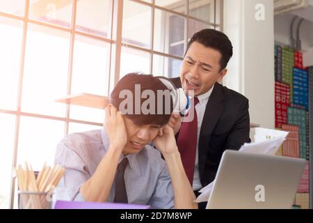 Un homme-Manager asiatique en colère criait dans un haut-parleur à l'oreille de son subordonné pour saisir des documents. Banque D'Images