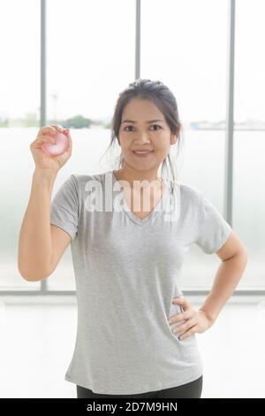 Femme asiatique gros plan jouant de l'équipement d'exercice, balle de caoutchouc, main se pressant dans la salle de gym. Banque D'Images
