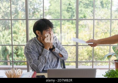 Une main qui livre des documents à un homme asiatique en difficulté avec de mauvaises nouvelles: Un entrepreneur désespéré est mis à pied, se cache pleurer, déçu par la faillite Banque D'Images