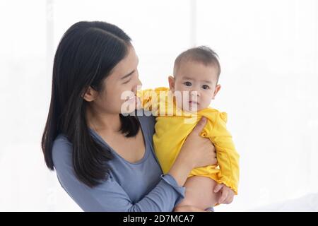 Une mère asiatique porte son bébé avec amour et soin. Banque D'Images