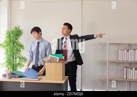 Un employé d'Asie a été congédié de son travail et emballait ses effets personnels dans des boîtes en papier avec un Manager debout par lui. Banque D'Images