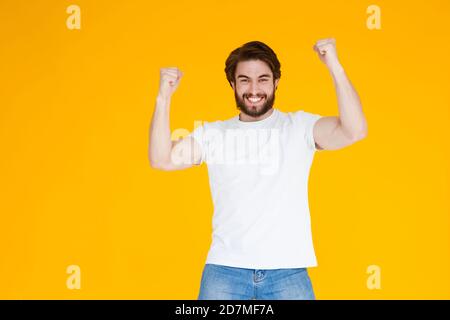 Portrait d'un homme barbu joyeux célébrant le succès isolé arrière-plan jaune Banque D'Images