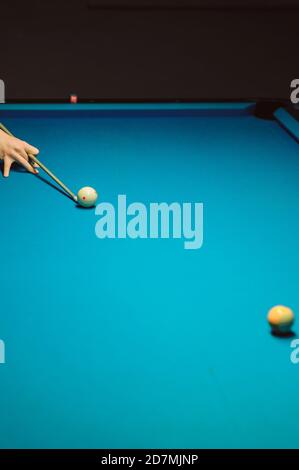 Plan vertical de la main avec le repère pointant sur un boule sur table de billard bleue Banque D'Images