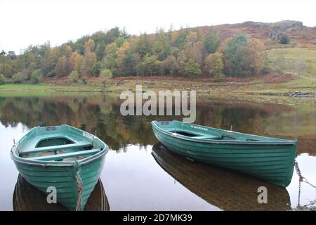 des bateaux à rames amarrés sur un lac calme entouré de collines et les arbres Banque D'Images
