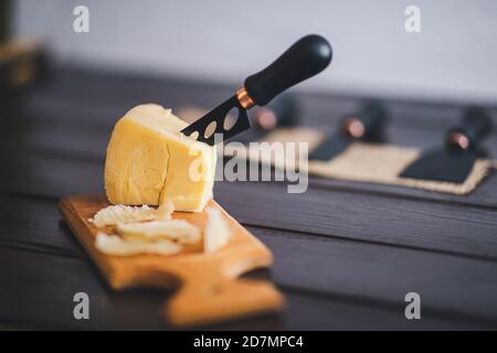 Détail cloesup composé, vue sur le cheddar vieilli avec couteau à fromage, sur fond de bois brun vintage Banque D'Images