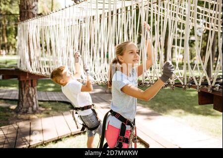 Les petits enfants courageux grimpent sur le filet dans le parc à cordes Banque D'Images
