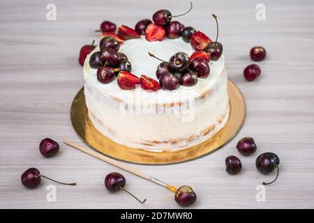 Cerises et fraises à l'or comestible sur le cheesecake à la noix de coco. Banque D'Images