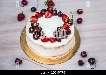 Cerises et fraises à l'or comestible sur le cheesecake à la noix de coco. Banque D'Images