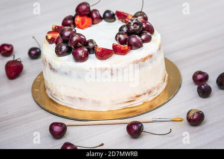 Cerises et fraises à l'or comestible sur le cheesecake à la noix de coco. Banque D'Images