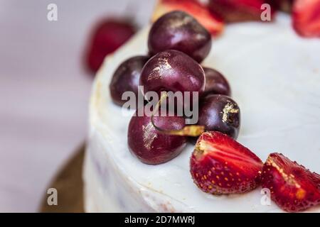 Cerises et fraises à l'or comestible sur le cheesecake à la noix de coco. Banque D'Images