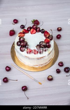 Cerises et fraises à l'or comestible sur le cheesecake à la noix de coco. Banque D'Images