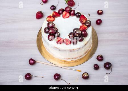 Cerises et fraises à l'or comestible sur le cheesecake à la noix de coco. Banque D'Images