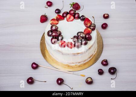 Cerises et fraises à l'or comestible sur le cheesecake à la noix de coco. Banque D'Images