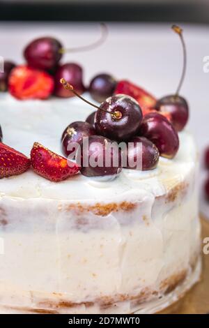 Cerises et fraises à l'or comestible sur le cheesecake à la noix de coco. Banque D'Images