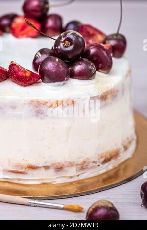 Cerises et fraises à l'or comestible sur le cheesecake à la noix de coco. Banque D'Images