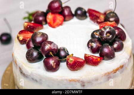 Cerises et fraises à l'or comestible sur le cheesecake à la noix de coco. Banque D'Images