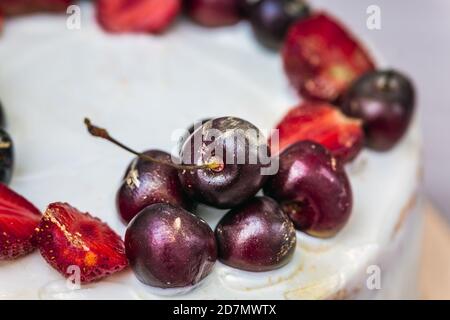 Cerises et fraises à l'or comestible sur le cheesecake à la noix de coco. Banque D'Images