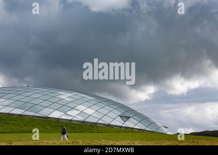 Un homme passe devant la Great Glasshouse au National Jardin botanique du pays de Galles dans le Carmarthenshire Banque D'Images