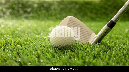 Équipement de sport de golf et concept de club. Bâton de golf prêt à frapper une balle sur la pelouse du parcours vert, réflexions de lumière du soleil, vue rapprochée. Banque D'Images