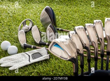 Équipement de golf, bâtons mis dans un sac gant et balles d'or sur la pelouse du parcours vert, vue rapprochée. Sport de golf et concept de club Banque D'Images