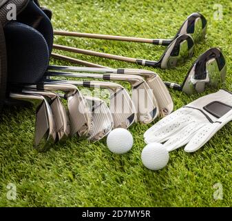 Équipement de golf, bâtons mis dans un sac gant et balles d'or sur la pelouse du parcours vert, vue rapprochée. Sport de golf et concept de club Banque D'Images