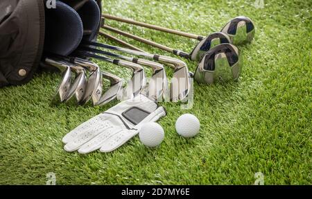 Équipement de golf, bâtons mis dans un sac gant et balles d'or sur la pelouse du parcours vert, vue rapprochée. Sport de golf et concept de club Banque D'Images