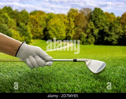 Main de golfeur dans un gant tenant un club, vue rapprochée. Parcours de golf, fond bleu ciel. Banque D'Images