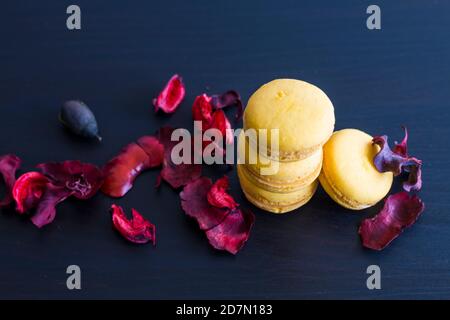 Petit déjeuner en gros plan avec des macarons jaunes au goût de citron. Gros plan du dessert français sur fond noir et fleurs autour dans un vin simple Banque D'Images