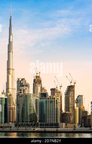 Vue imprenable sur les gratte-ciel de Dubaï au coucher du soleil avec le magnifique Burj Khalifa réfléchi sur le canal d'eau qui coule en premier plan. Banque D'Images