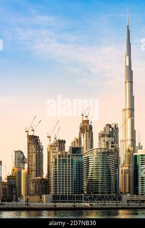 Vue imprenable sur les gratte-ciel de Dubaï au coucher du soleil avec le magnifique Burj Khalifa réfléchi sur le canal d'eau qui coule en premier plan. Banque D'Images