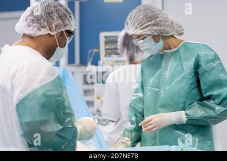 Deux chirurgiens en vêtements de travail de protection se replient sur le patient pendant l'opération Banque D'Images