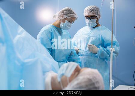 Jeune femme assistante en vêtements de travail de protection préparant des instruments médicaux Banque D'Images